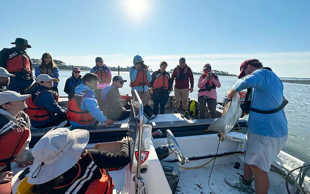 VIMS ESL Seawater Lab Manager John Lewis (right) shows students a cownose ray, which was quickly returned to the water. Photo by Ethan Smith.