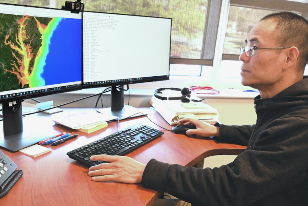 Dr. Joseph Zheng with the Center for Coastal Resources Management at the Batten School & VIMS views a SCHISM simulation on his computer that shows different colors on a map of the Chesapeake Bay..