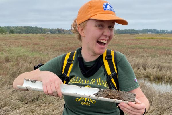 Researcher in a marsh holds sediment core
